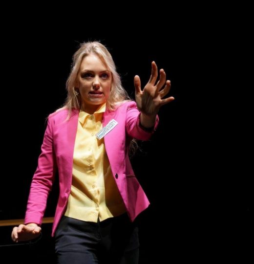a woman in a pink blazer with her hand outstretched